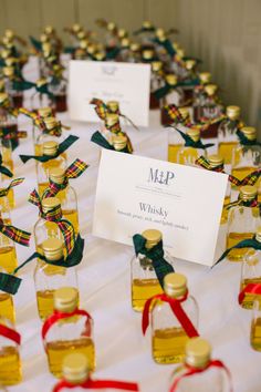 many small bottles are lined up on a table with red and green ribbon around them