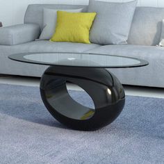 a glass table sitting on top of a blue rug in front of a gray couch