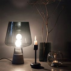 a table topped with a lamp next to two vases and a candle holder on top of a table