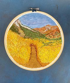 a cross - stitch pattern is hanging on a wall with a mountain scene in the background