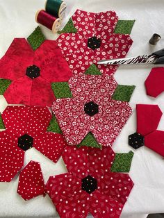 several pieces of red and green fabric are laid out on a table with sewing supplies