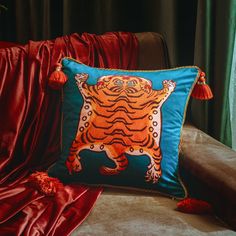 a pillow with a tiger on it is sitting on a couch in front of a red curtain