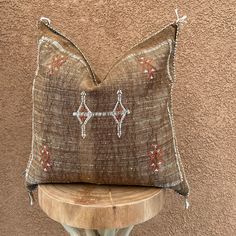 a decorative pillow sitting on top of a wooden table next to a brown and white wall