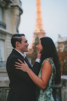 a man and woman standing next to each other in front of the eiffel tower