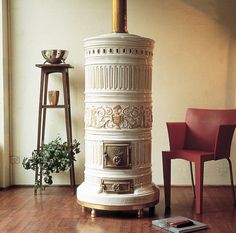 a white stove sitting on top of a hard wood floor next to a red chair