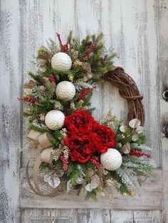 a wreath with red flowers and white balls hanging on a wooden doorknott