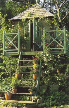 a gazebo surrounded by plants and flowers in front of a house with steps leading up to it