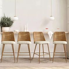 four stools in front of a white wall with plants on the table and hanging lights above them