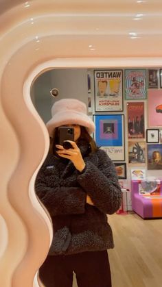 a woman taking a selfie in front of a mirror with pictures on the wall