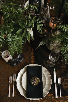 the table is set with silverware and greenery