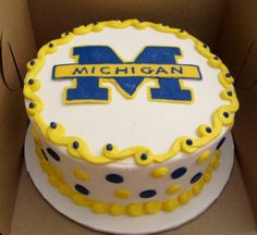 a cake in a box with the michigan m logo on it's frosting