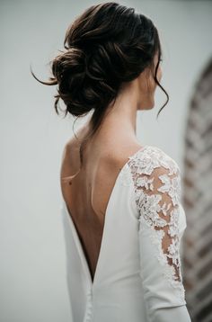 the back of a woman's white dress with long sleeves and lace on it