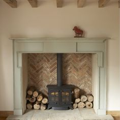 a fireplace with logs stacked on top of it and a wood burning stove in the middle