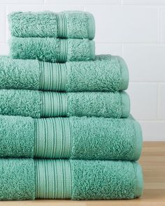 a stack of green towels sitting on top of a wooden table