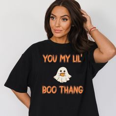 "\"Get Ready to Haunt the Laughs with Our Ghost Shirt - 'You My Lil Boo Thang'!  Looking for a hilarious twist on Halloween fashion? Look no further! Our Ghost Shirt is the perfect addition to your wardrobe for a dose of laughter and spooky charm. With the cheeky message 'You My Lil Boo Thang,' this funny Halloween shirt is sure to turn heads and spark conversations. Whether you're planning a night of Halloween fun or just want to add a touch of humor to your day, our Ghost Shirt has you covered Funny Halloween T-shirt With Screen Print, Black Slogan T-shirt For Halloween, Black Novelty Tops With Slogan, Black Novelty Top With Slogan, Halloween Novelty Tops With Funny Text, Funny Halloween Tops With Text, Halloween Fun T-shirt With Funny Text, Funny Halloween T-shirt With Text Print, Funny Halloween Text Print T-shirt