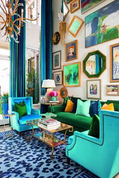 a living room filled with blue and green furniture next to a wall covered in pictures