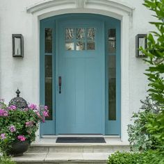 a blue front door with two potted plants