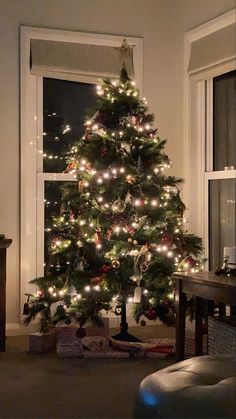 a lit christmas tree in front of a window