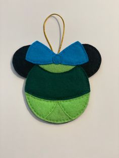 a mickey mouse ornament with a blue bow on it's head and green ears