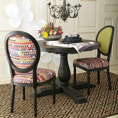 a dining room table with two chairs and a chandelier