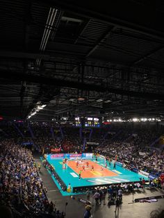 an indoor tennis court with people watching it