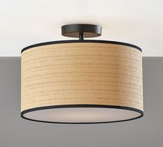 a light fixture with a beige shade on the bottom and black trim around it, against a white background