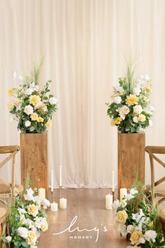 two tall wooden vases filled with white and yellow flowers on top of a table