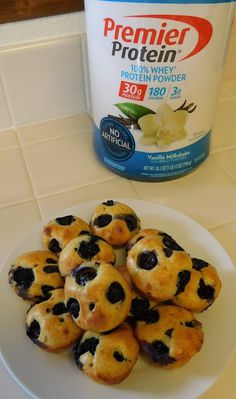 blueberry muffins on a white plate next to a bottle of protein powder