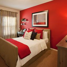 a bedroom decorated in red and white with a bed, nightstands, potted plant and pictures on the wall