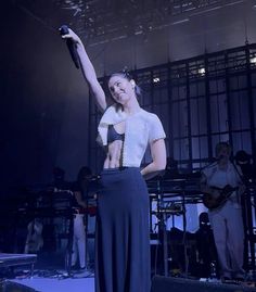 a woman standing on top of a stage with her arms in the air and holding a microphone