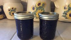 two jars with sunflowers painted on them sitting on a kitchen counter next to teapots