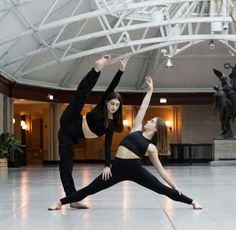 two women are doing yoga in a large room