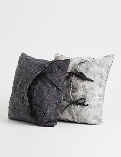 two black and white pillows sitting next to each other on top of a white surface