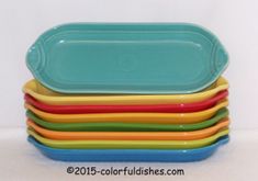 a stack of multicolored dishes sitting next to each other on a white surface