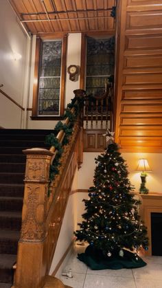 a christmas tree sitting on top of a wooden banister next to a stair case