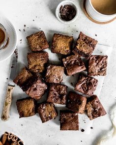 chocolate brownies cut into squares on a cutting board next to some spices and a cup of coffee