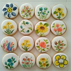 a bunch of decorated cookies sitting on top of a white countertop with flowers painted on them