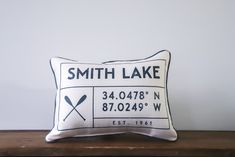 a white pillow with a black and white sign on it that says smith lake, 34 0479 w