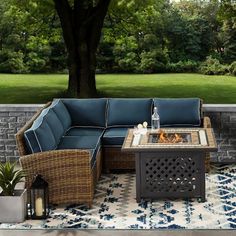 an outdoor patio furniture set with fire pit and seating on the side of a brick wall