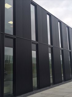 the side of a building that has many windows on it and is made out of black slats