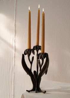 two candles are sitting on a table with white linens and a wall in the background