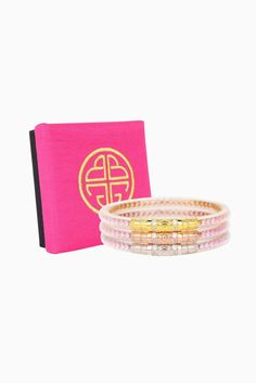 two bracelets and a pink book on a white background