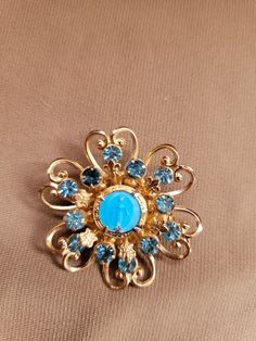 The brooch has a blue hand painted Mother Mary portrait set in an open floral design with 3 carats of Swiss blue topaz.  14K gold plated. Blue Hallmarked Brooches For Anniversary, Formal Blue Gemstone Brooches, Formal Blue Gemstone Brooch, Elegant Blue Gemstone Brooch, Elegant Blue Gemstone Brooches, Collectible Hallmarked Blue Brooches, Antique Blue Jewelry With Brooch, Collectible Gold Brooches With Gemstones, Elegant Turquoise Brooches For Collectors