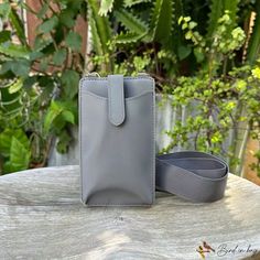 a small gray purse sitting on top of a wooden table next to a planter