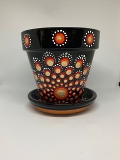 a black and orange flower pot sitting on top of a saucer