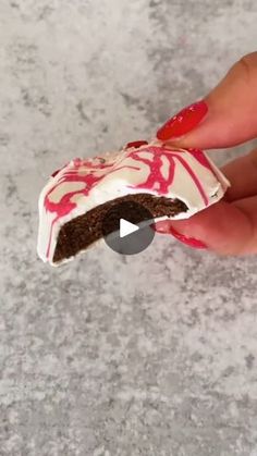 someone is holding a piece of cake with red and white icing on it's side