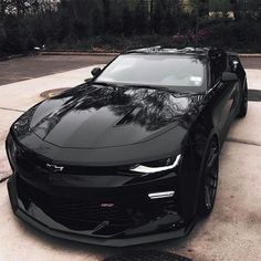 a black chevrolet camaro is parked in the driveway