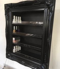 an ornate black shelf with many bottles on it and a mirror in the corner behind it