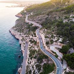 an aerial view of a winding road next to the ocean