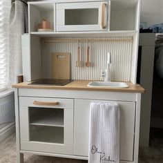 a toy kitchen with white cabinets and wooden counter tops